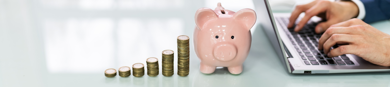 stack of coins and piggy bank next to laptop